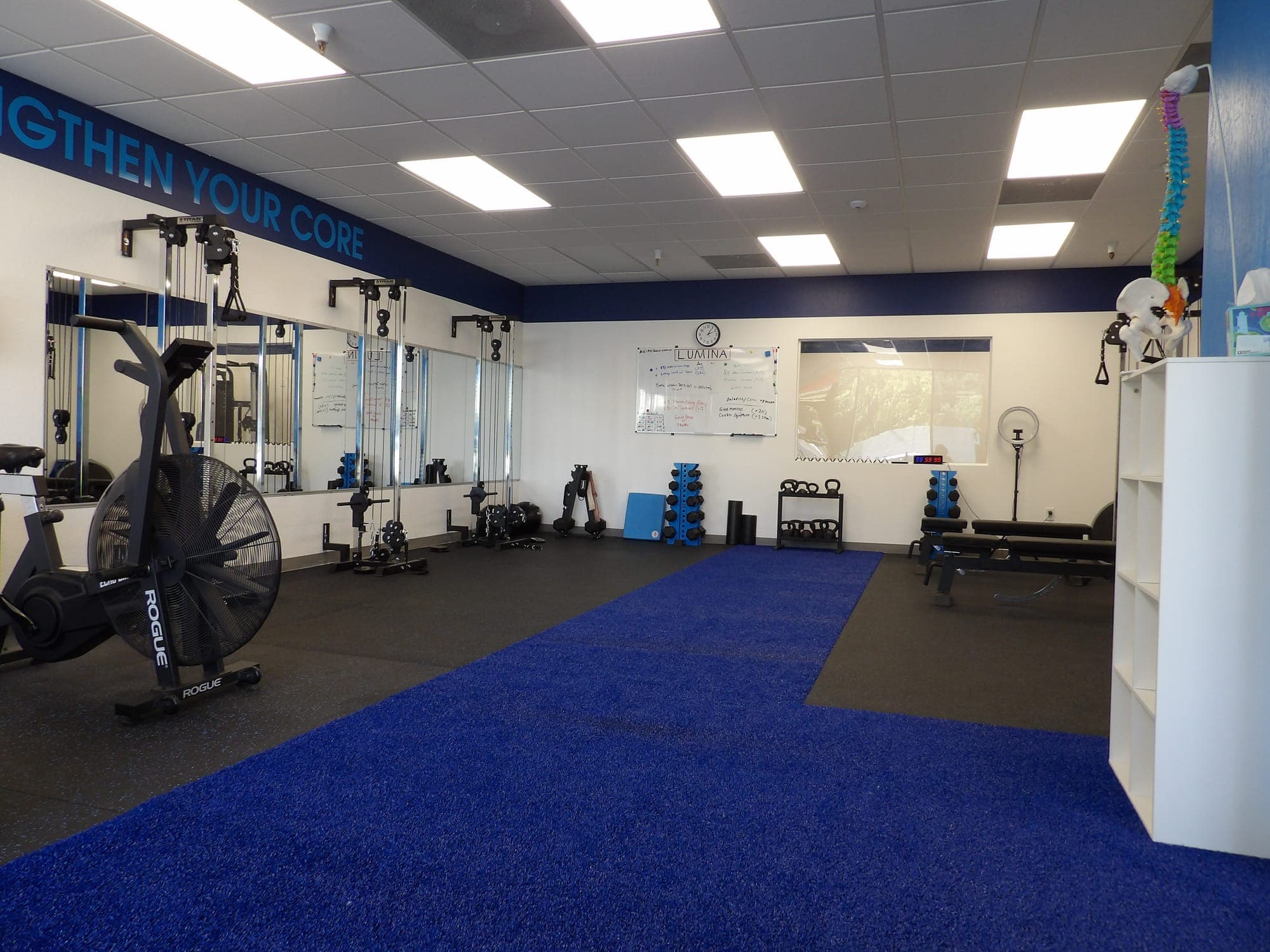 The LUMINA studio inside Fyzical in South Reno: cable machines, dumbbells, benches and a turf lane under a Strengthen Your Core banner